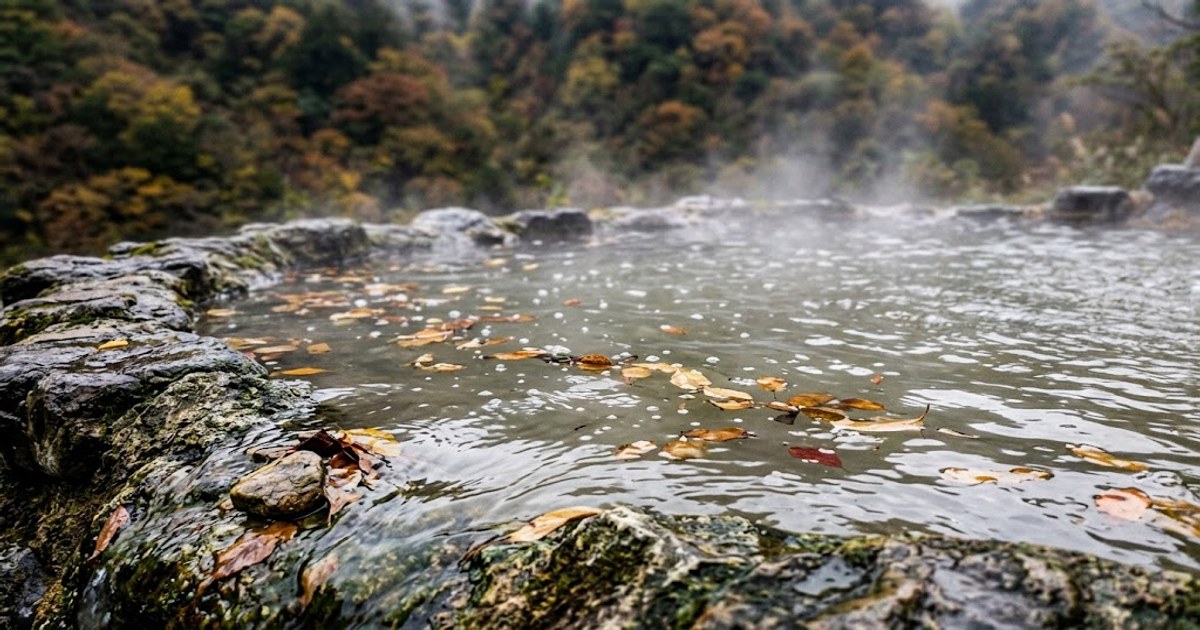 秋日露天溫泉池水面冒著熱氣,池緣是長滿青苔的岩石